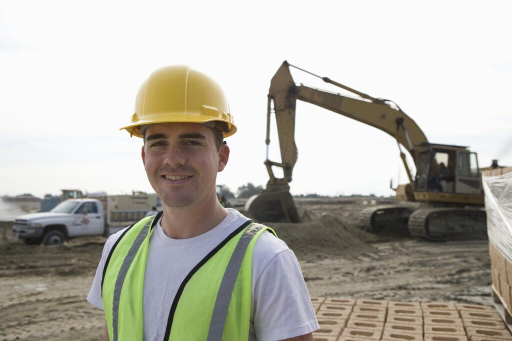 a man in a hard hat and safety vest standing in front of a construction site